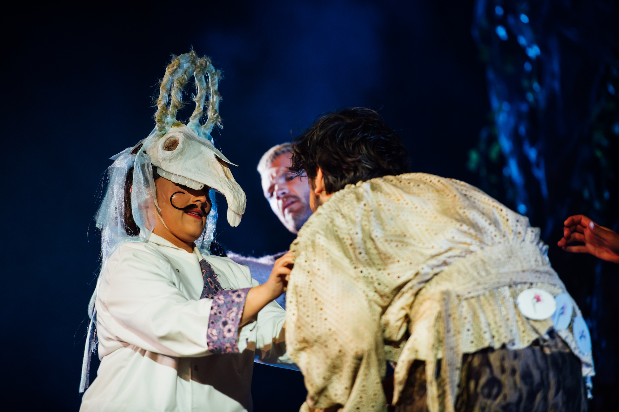 Actors on stage in A Midsummer Night's Dream, one wearing a creature costume with a moustache.