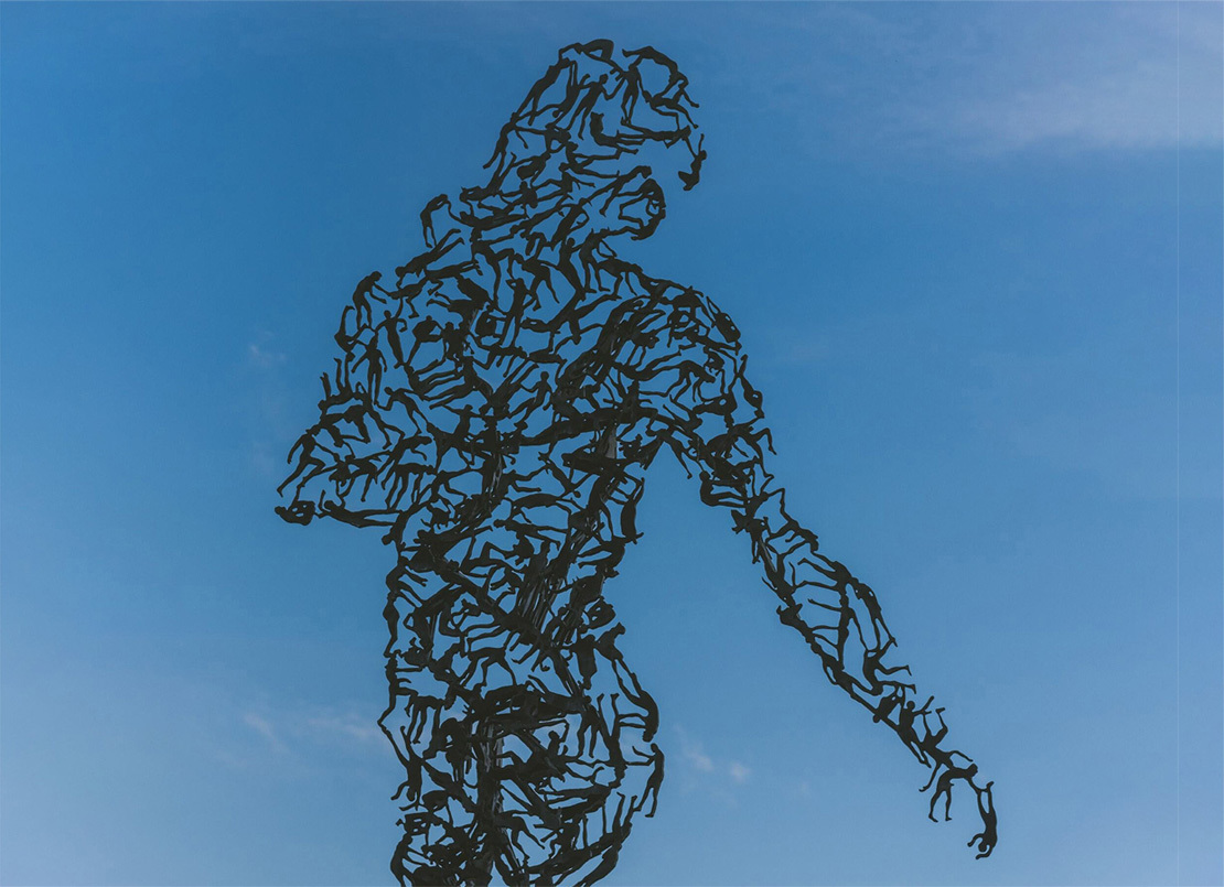 Several small human silhouettes placed together to form a larger human figure looking around to the right with one arm stretched out, with a blue sky background.