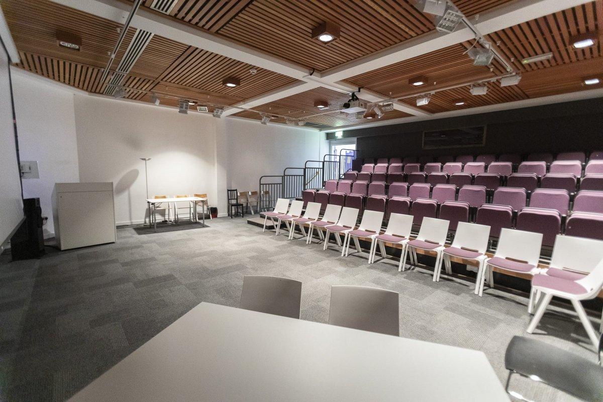 Empty lecture theatre with several rows of seats situated on the right-hand side.