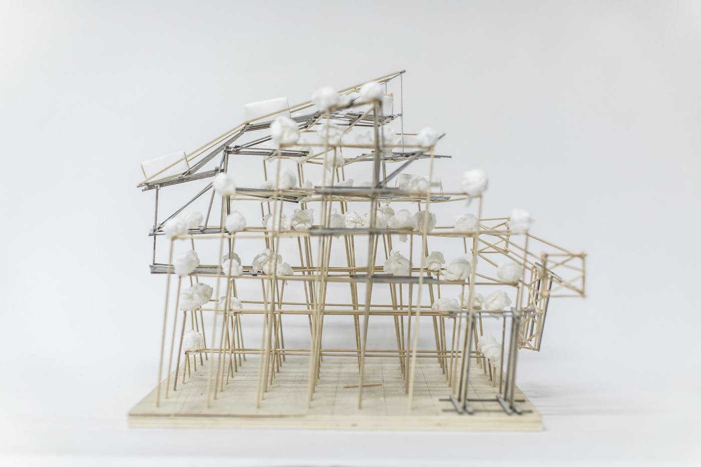 Architectural model of a multi storey building made of wooden and metal rods, viewed from the side.