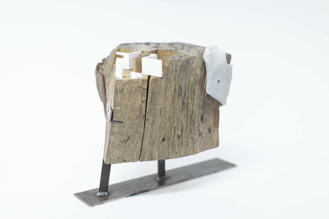 A sculpture made of chipped wood with resin and a metal base, standing on a plain white surface.