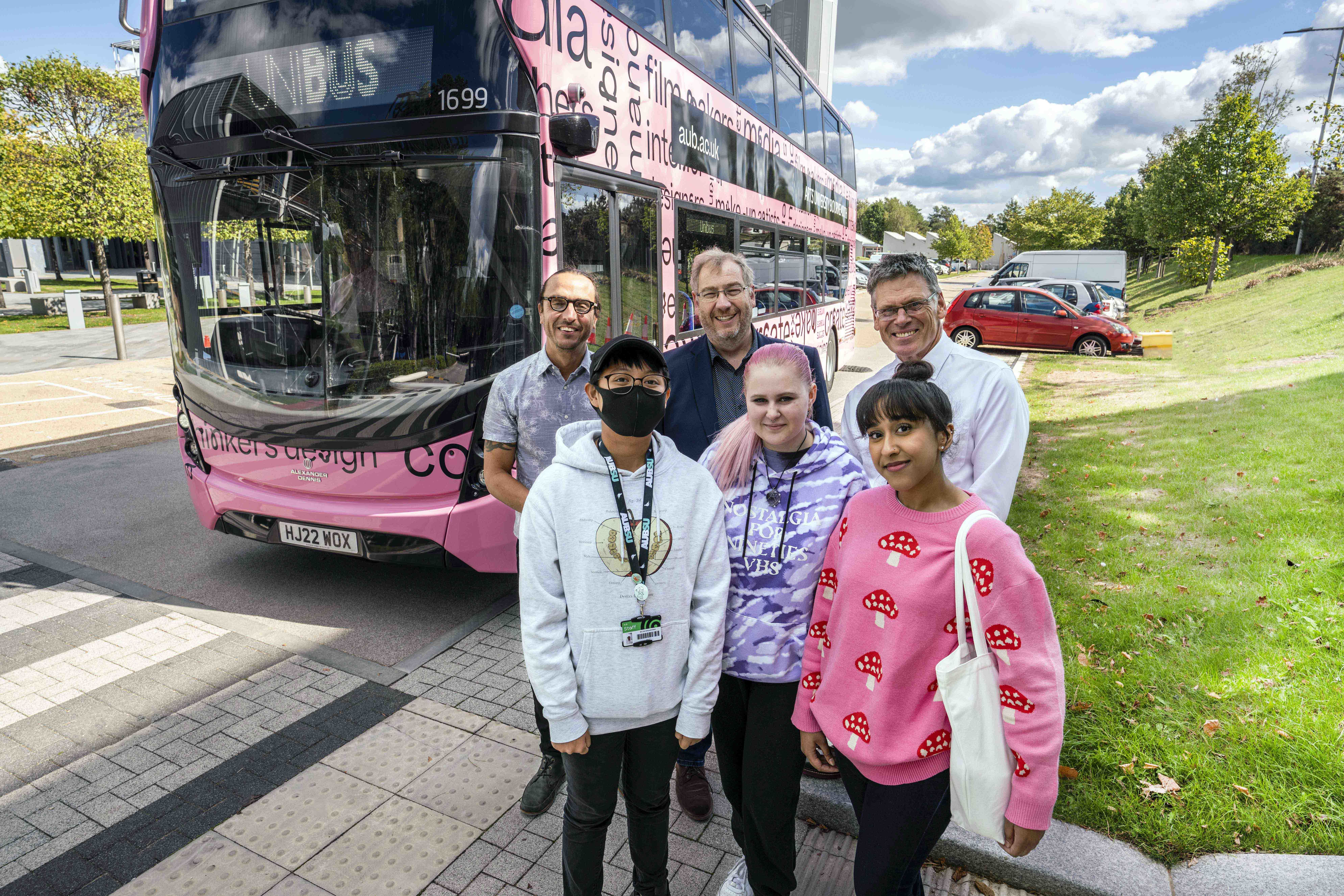 Staff and students stand beside AUB's newly branded UniBus service