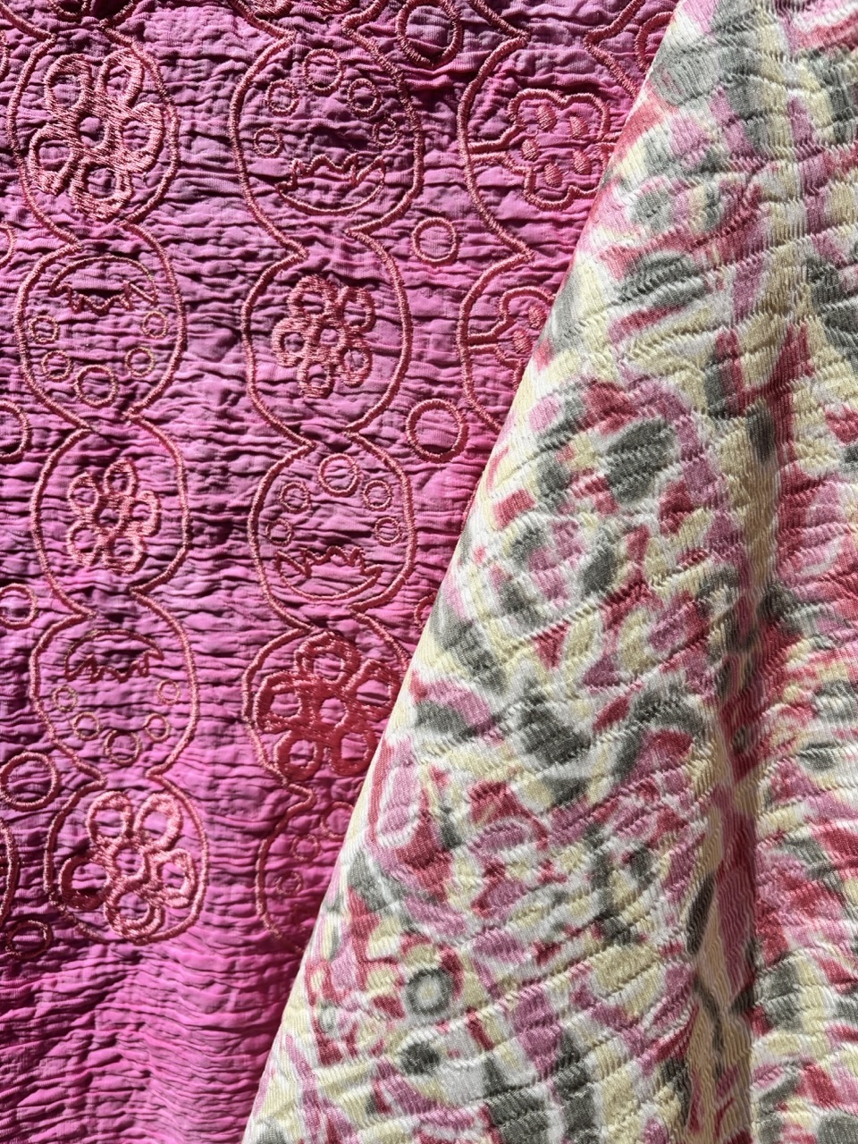 Pink quilted fabric with circular stitched patterns alongside folded textile with geometric print in pink, green and cream colours.