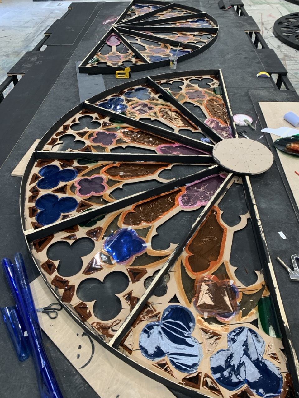 Large, round wood stained glass window painted with colour in a workshop for AUB Productions' 'I, Joan'.