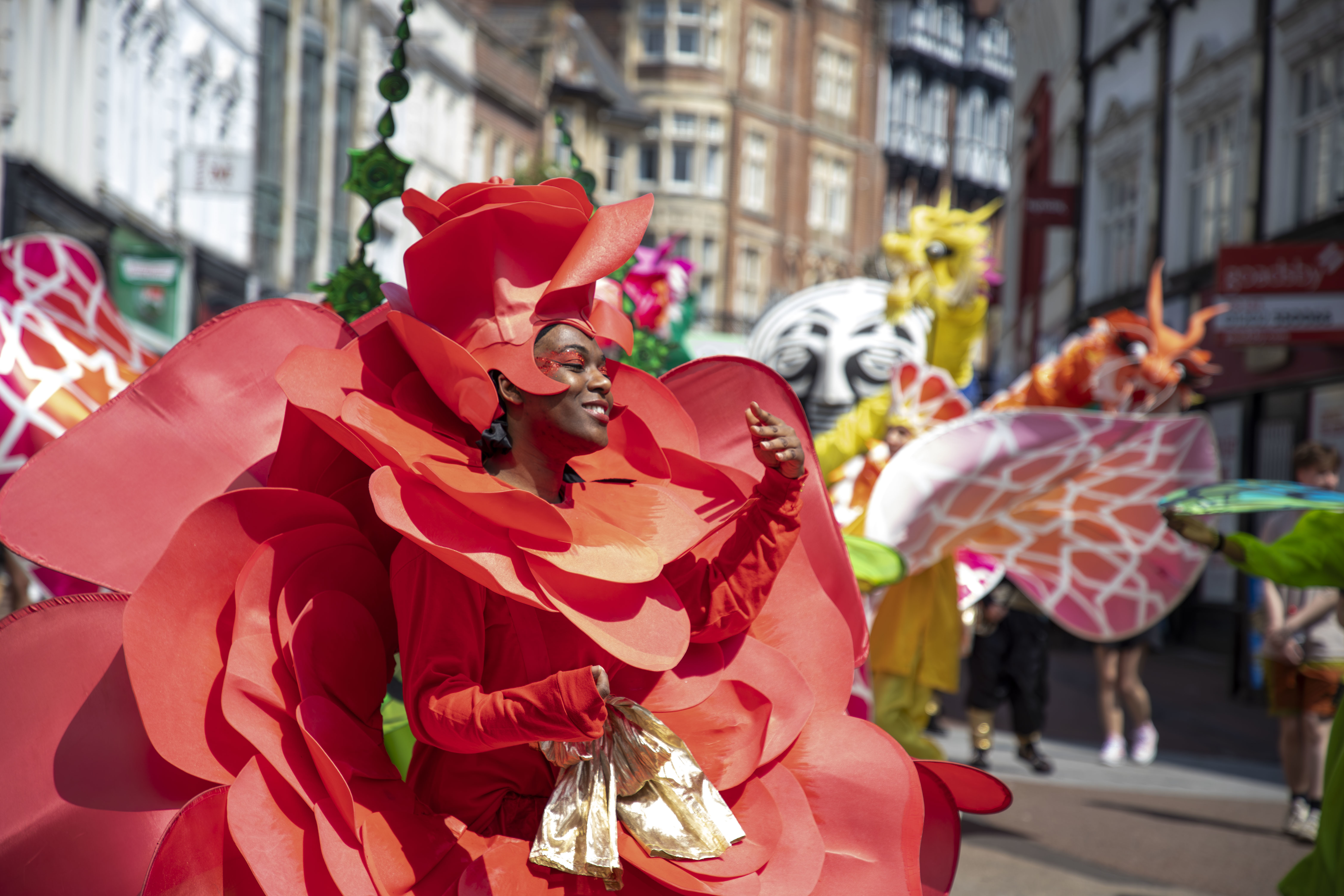 A carnival performer dressed in a colourful rose costume during Alice in Spring on Bournemouth high street.