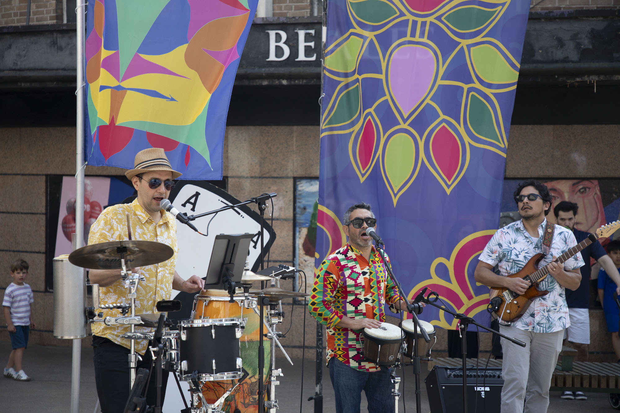 Three musicians performing in front of Beales on Bournemouth high street  at the 2024 Alice in Spring event.