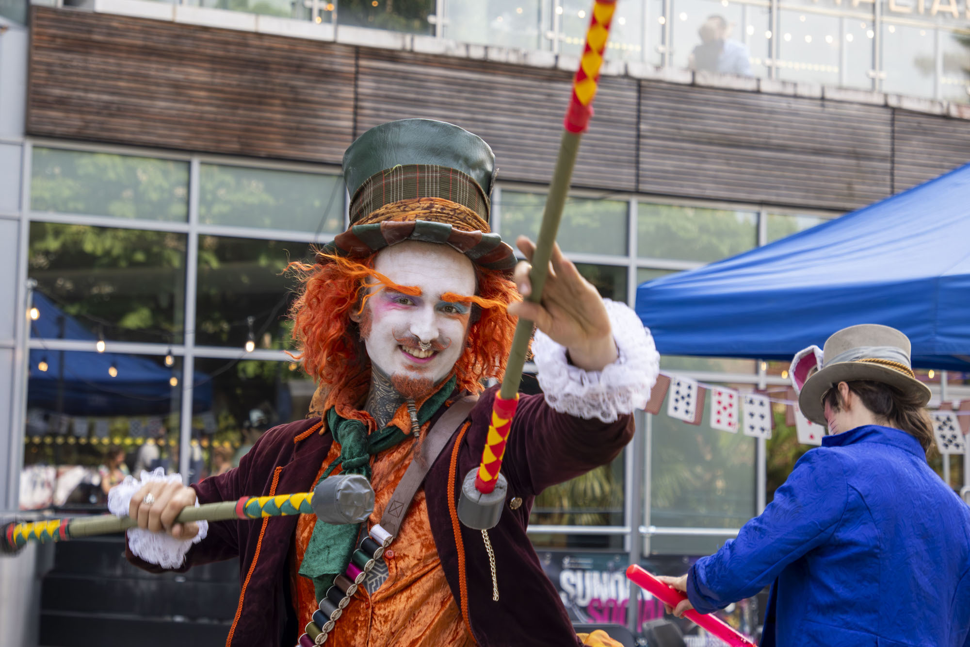 A performer dressed as the Mad Hatter from Alice in Wonderland with two juggling batons at the 2024 Alice in Spring event in Bournemouth.