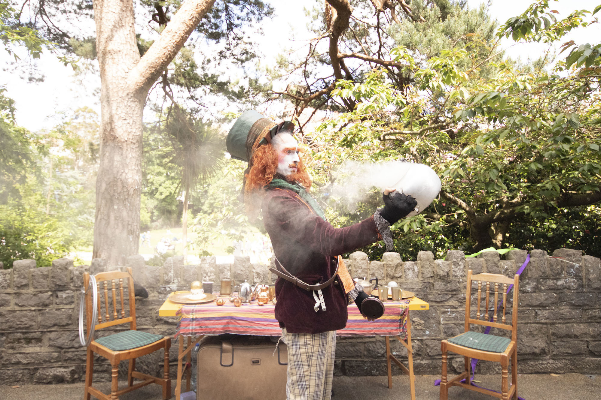 A person in costume as The Mad Hatter stands by a wall in Bournemouth.