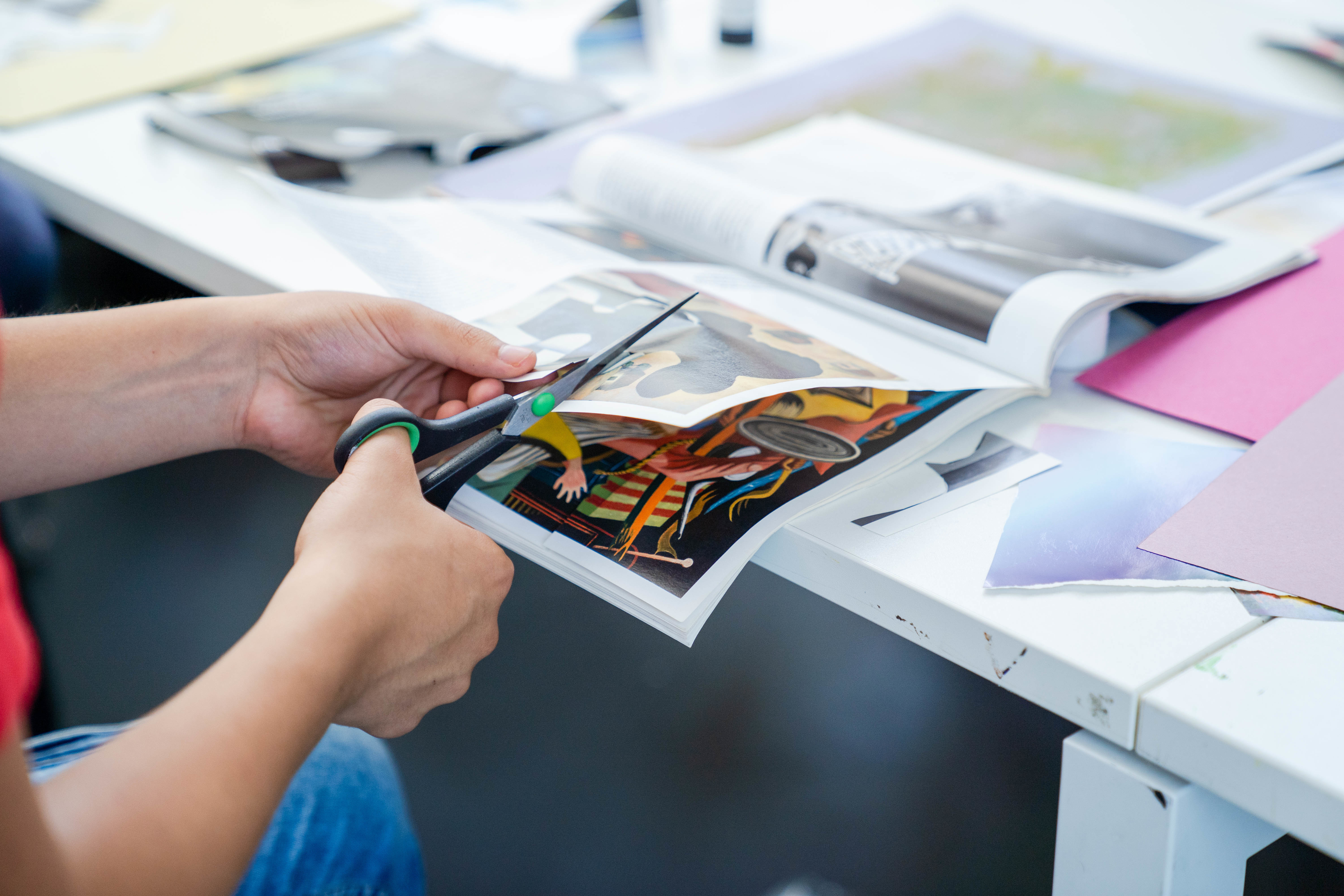 Student cutting up images from a magazine for collaging