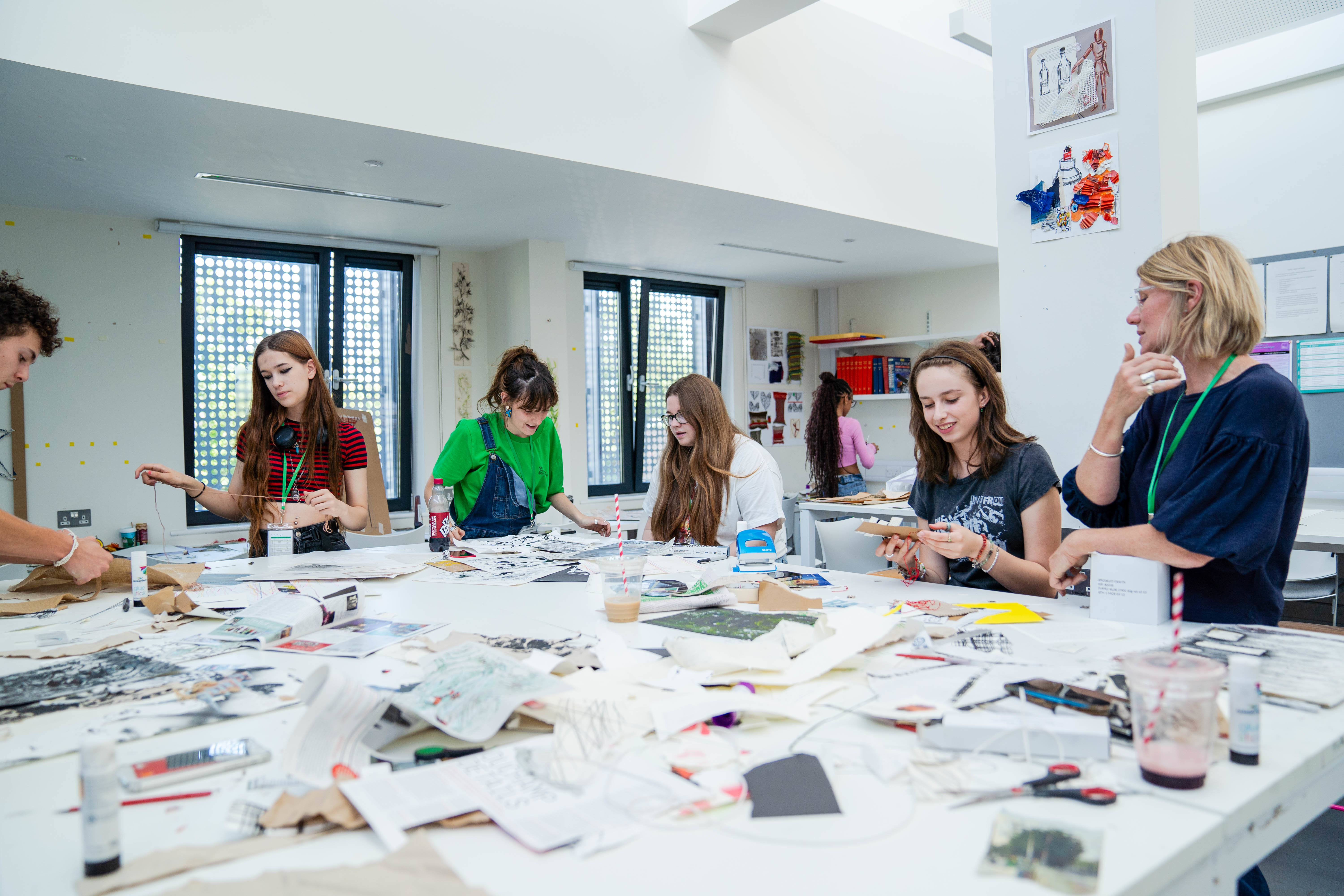 Students gathered around table experimenting with mix media art materials guided by AUB Tutor