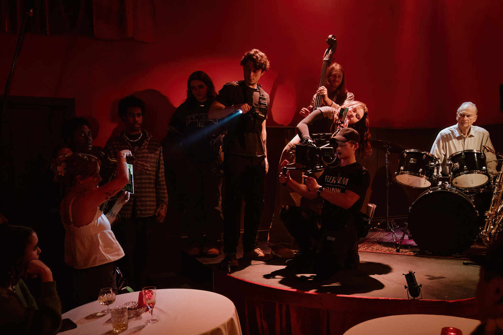 Members of a film crew standing on a stage in a blues club, shining a light on a clapper board.