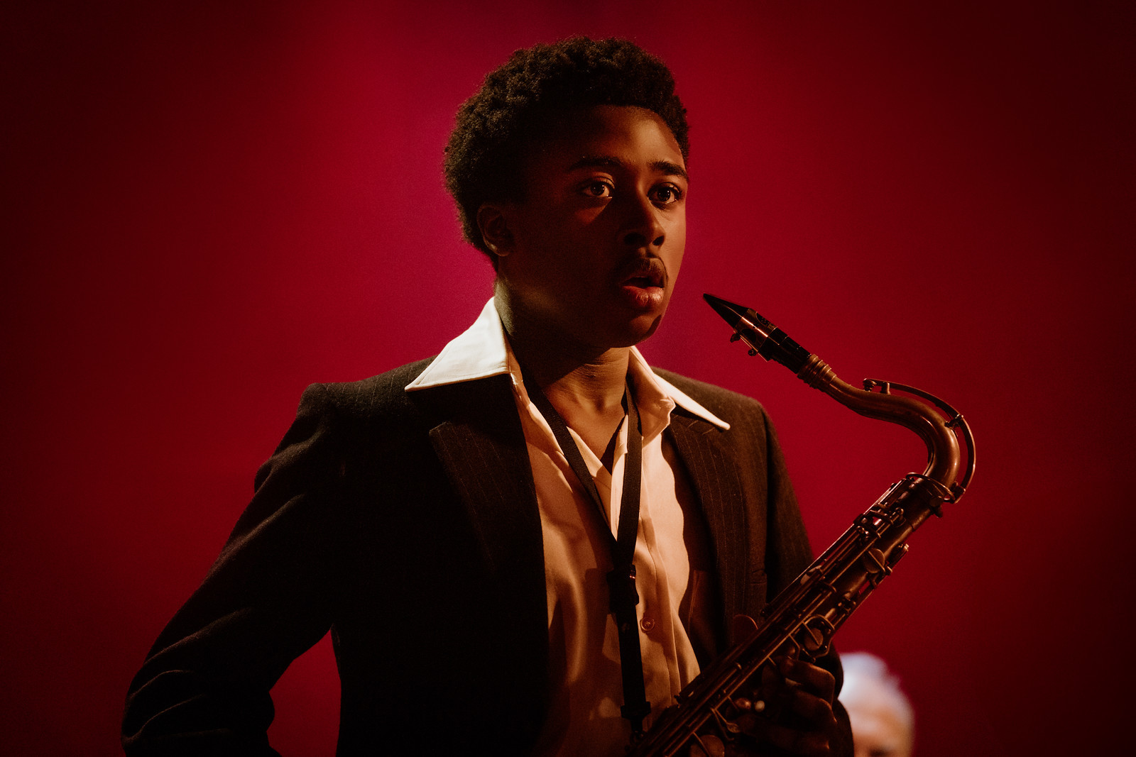Film still of a young musician playing the saxophone with a surprised expression.