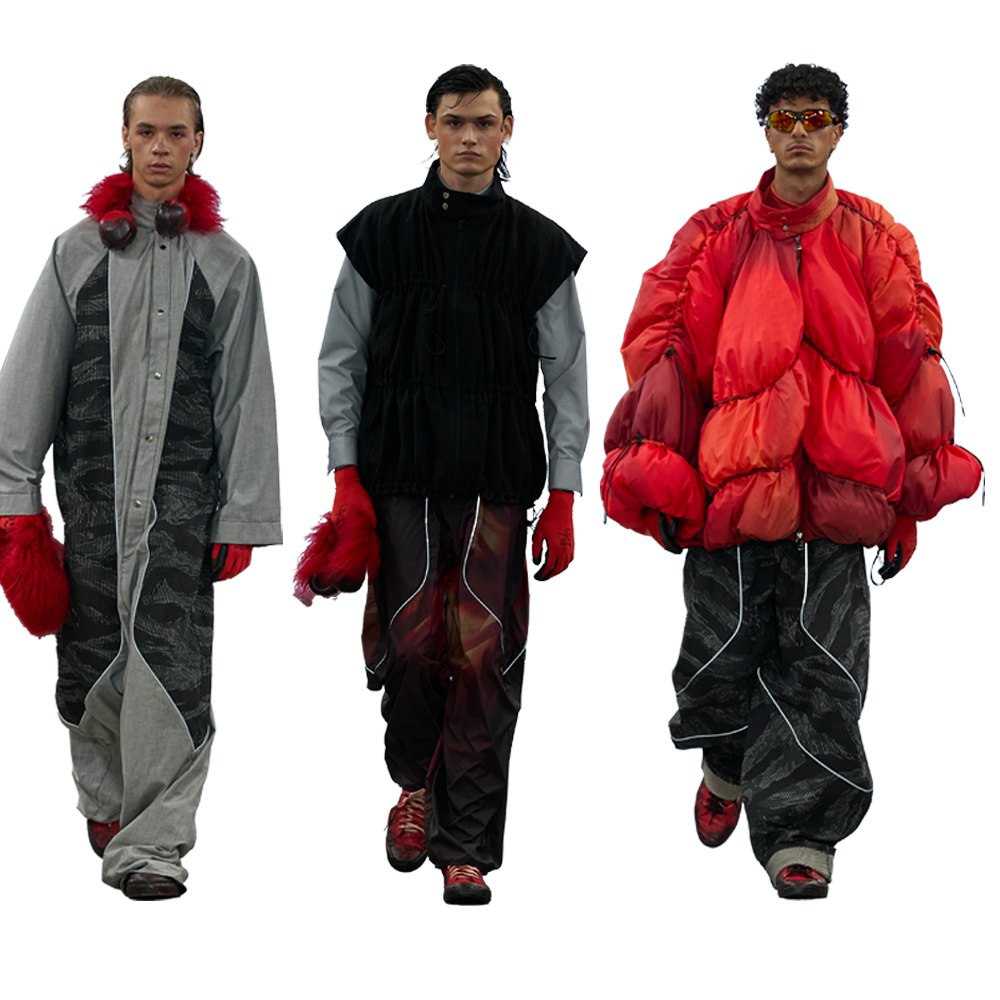 Three male models walking in avant-garde fashion: grey coat with red fur trim, black vest with green sleeves, bright red puffy jacket.