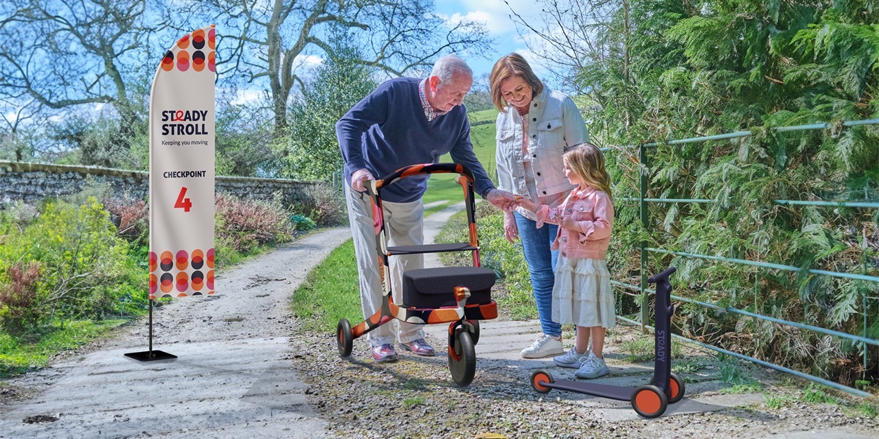 An older adult is holding onto a colourful mobility aid whilst taking a flower from a child and another adult looks on.