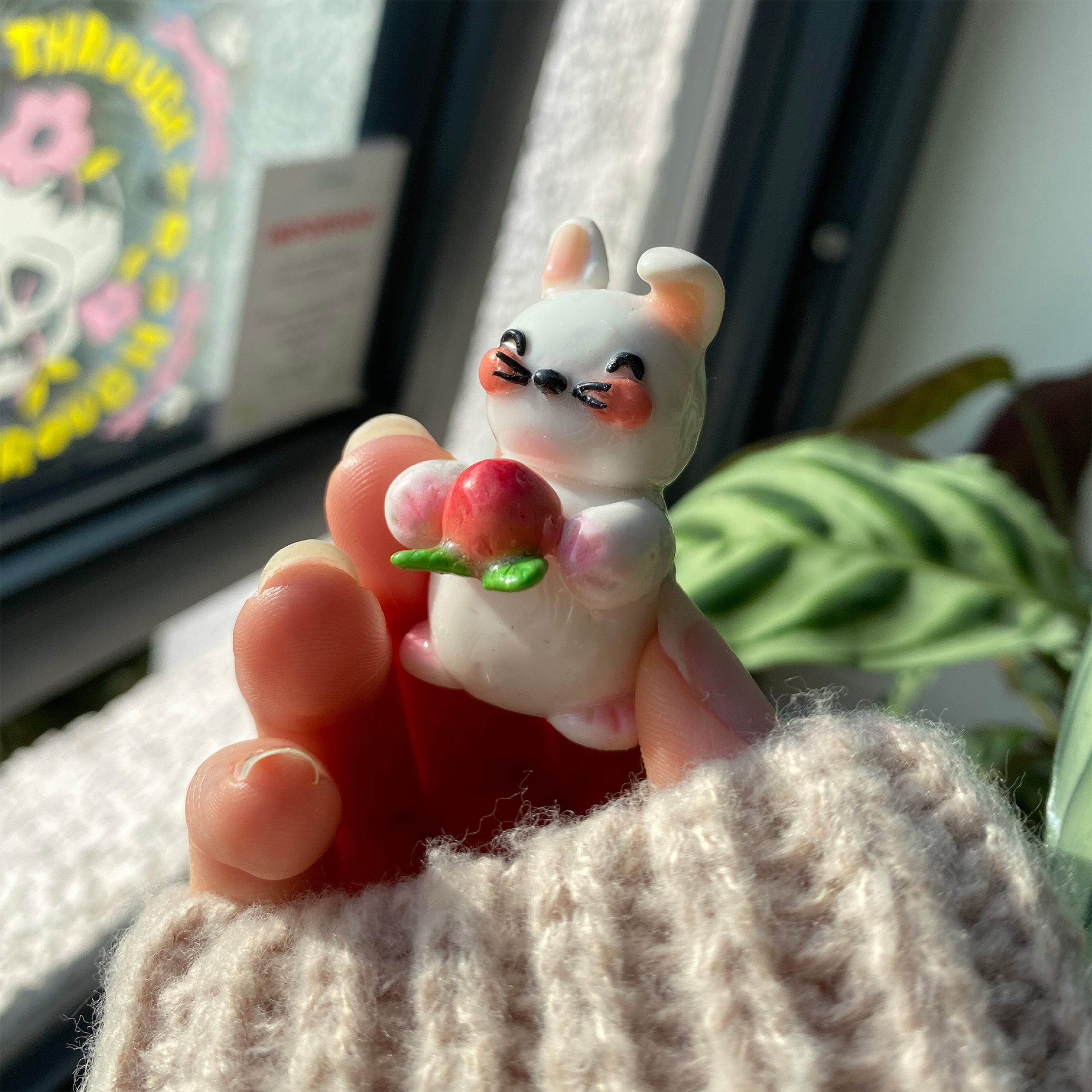 A small handmade polymer clay ornament – a mouse holding an apple