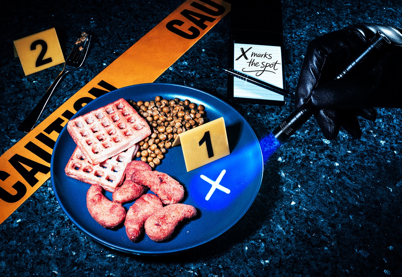 A blue plate holds three pieces of pink meat, brown grains, and two square waffles, with numbered evidence markers and a caution tape in the background. A gloved hand points with a pen towards a marker labelled 'X'.