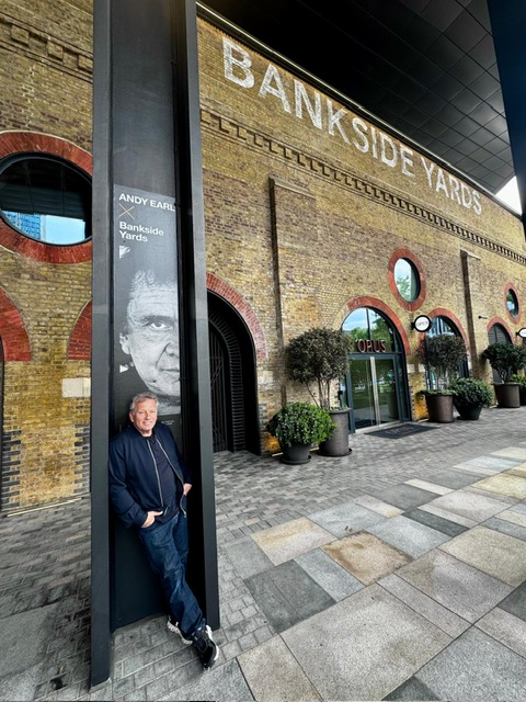 Andy Earl stood in a black pillar at Bankside Yards, tall brick building in the background with arches.