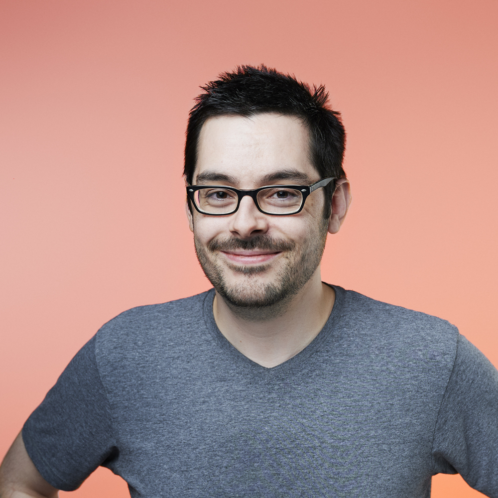 Headshot of Andy Stevens, peach background.