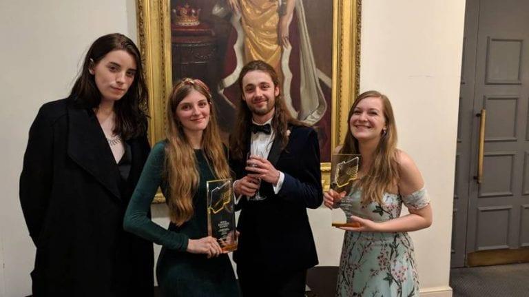 Four people stand and pose for a photo with a trophy at the RTS Regional Awards