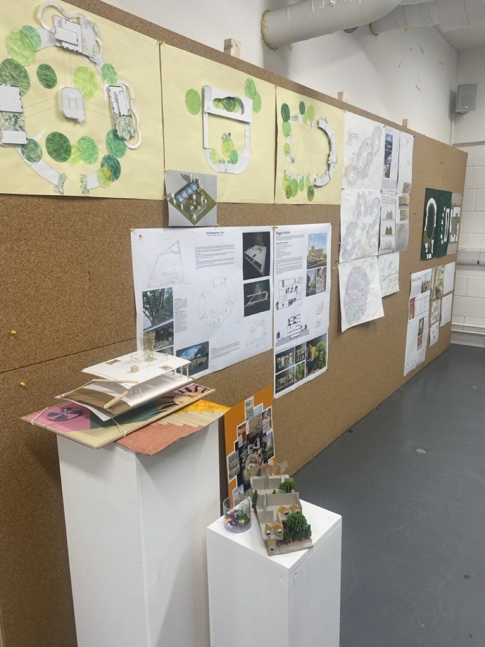 Architecture work on large cork panelling, green trees and models.