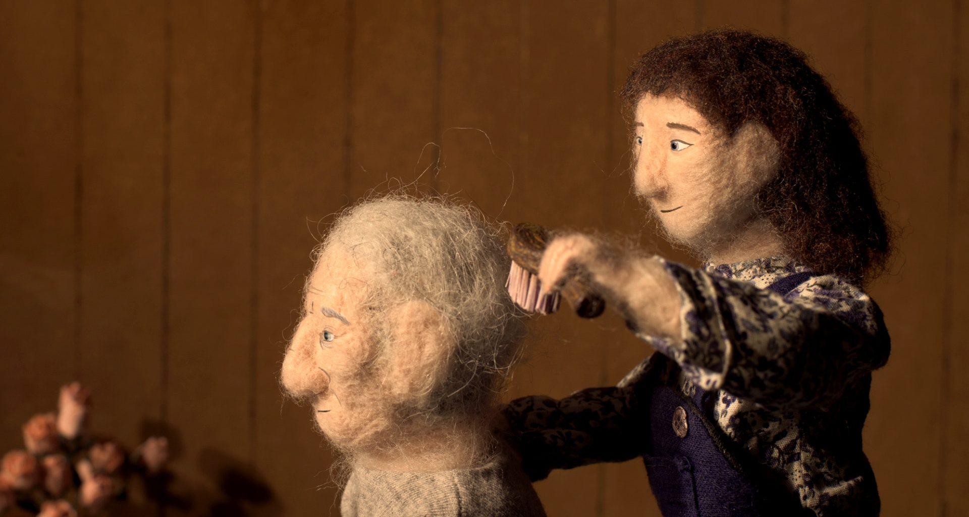 Animated film still showing a woollen girl brushing the hair of a woollen older person.