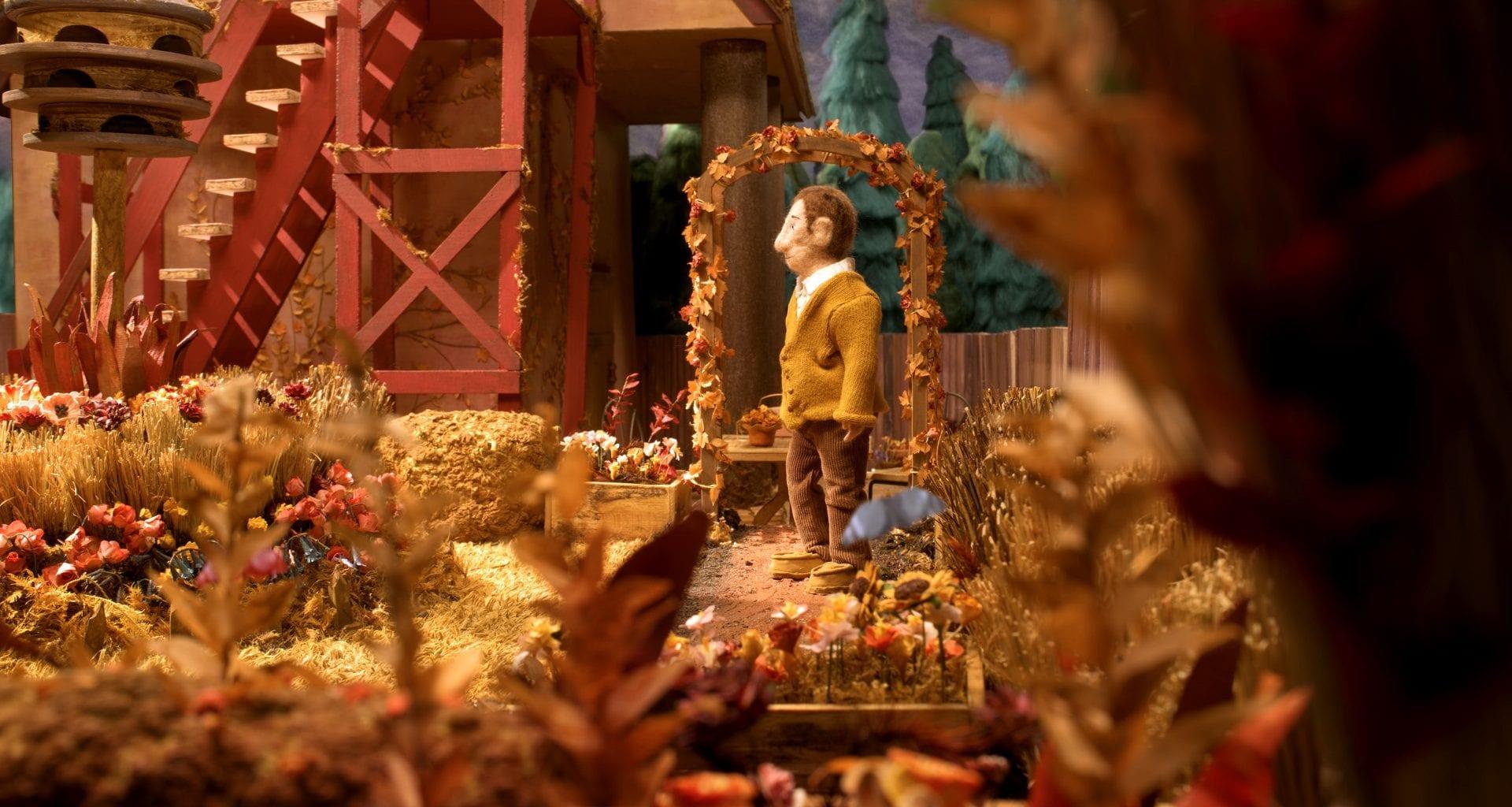 A model figure stands in an autumnal scene with an archway behind them and a staircase to their left.