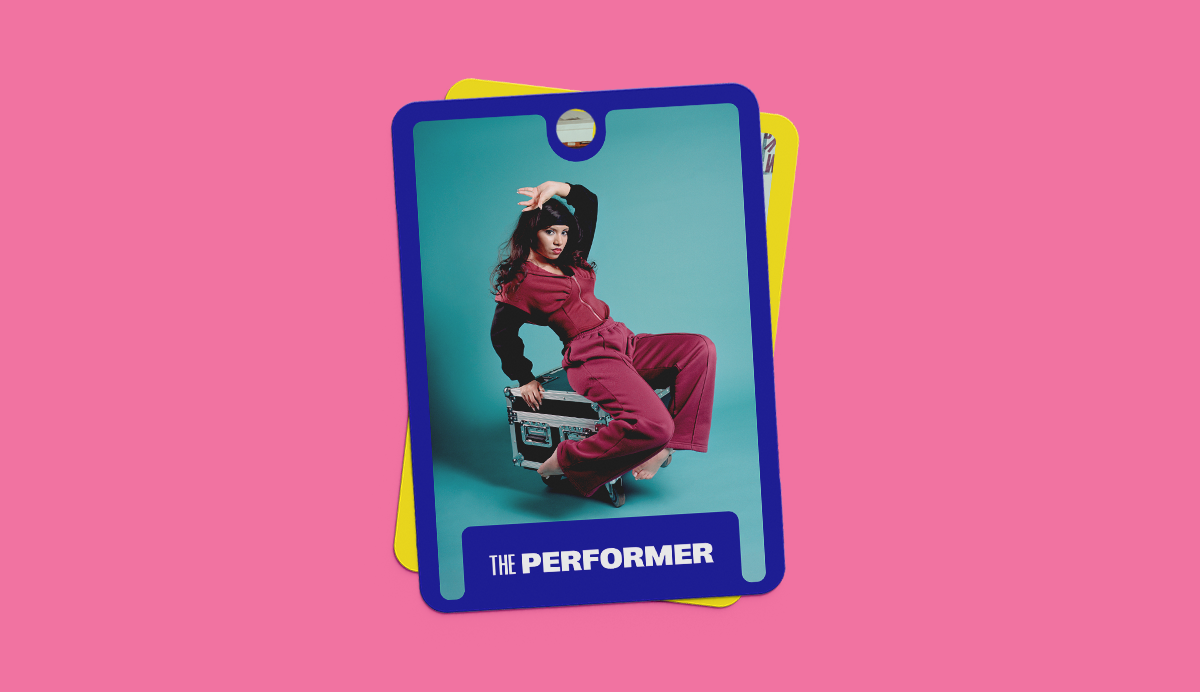 Trading card with blue border on pink background shows person in red tracksuit sitting on metal stool against turquoise backdrop