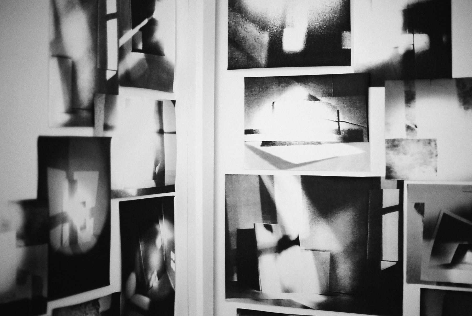 Black and white abstract images printed and stuck on top of one another on a wall.