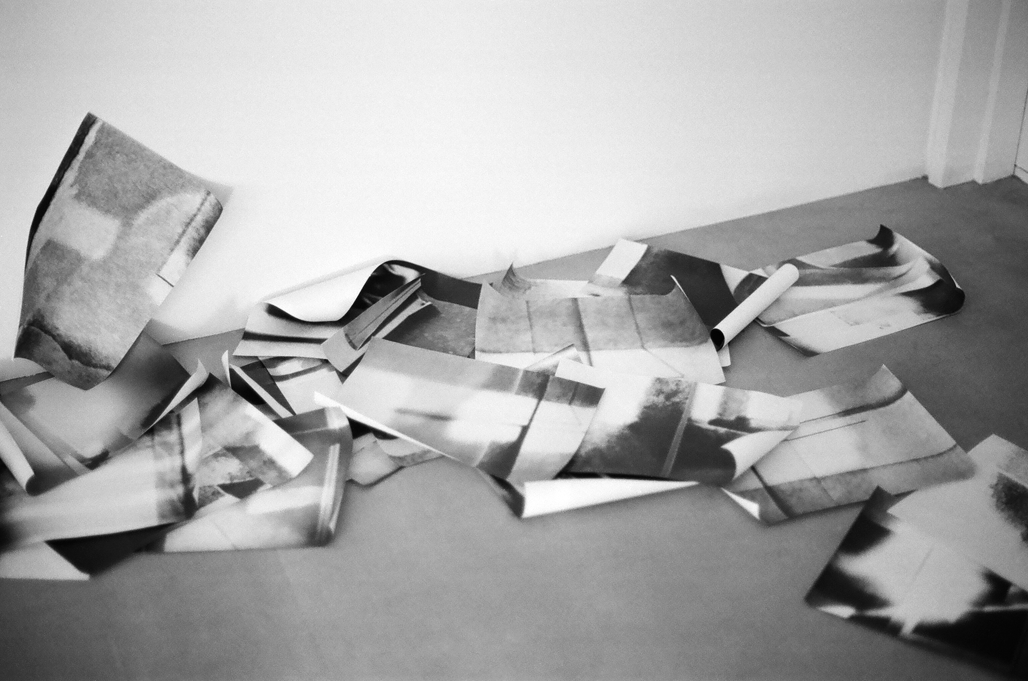 Several black and white photos printed onto paper lying strewn across the floor.