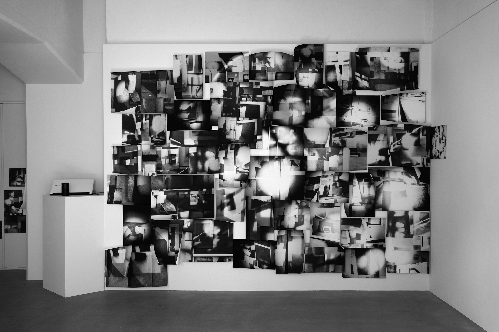 A large collage of black and white abstract photos stuck to a wall.