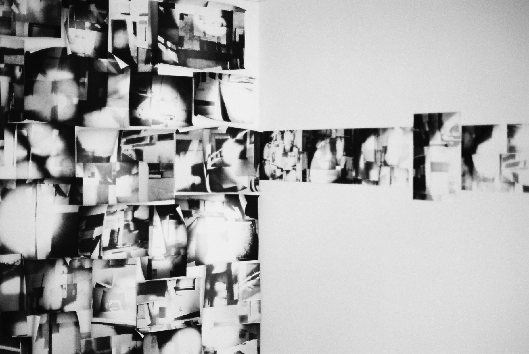 Part of a collage of black and white abstract photos stuck to a wall.