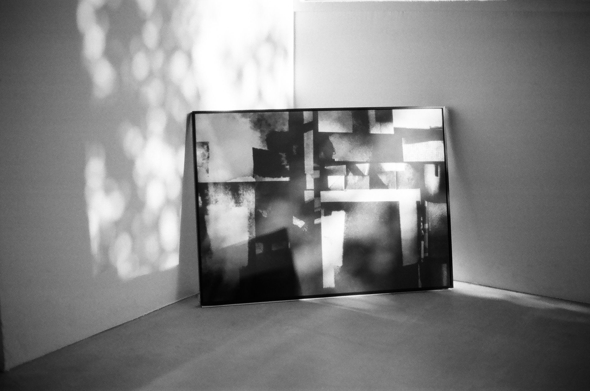 A large canvas sitting in a corner of a room with an abstract black and white photo printed on it.