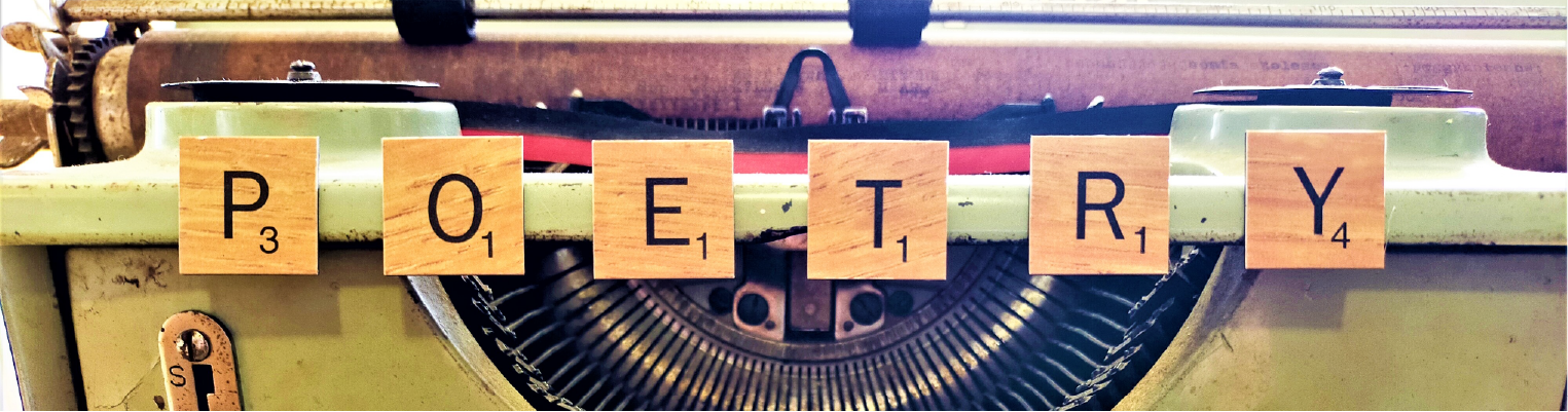 Close-up of a typewriter and keys with Scrabble tiles arranged to spell 'Poetry'.