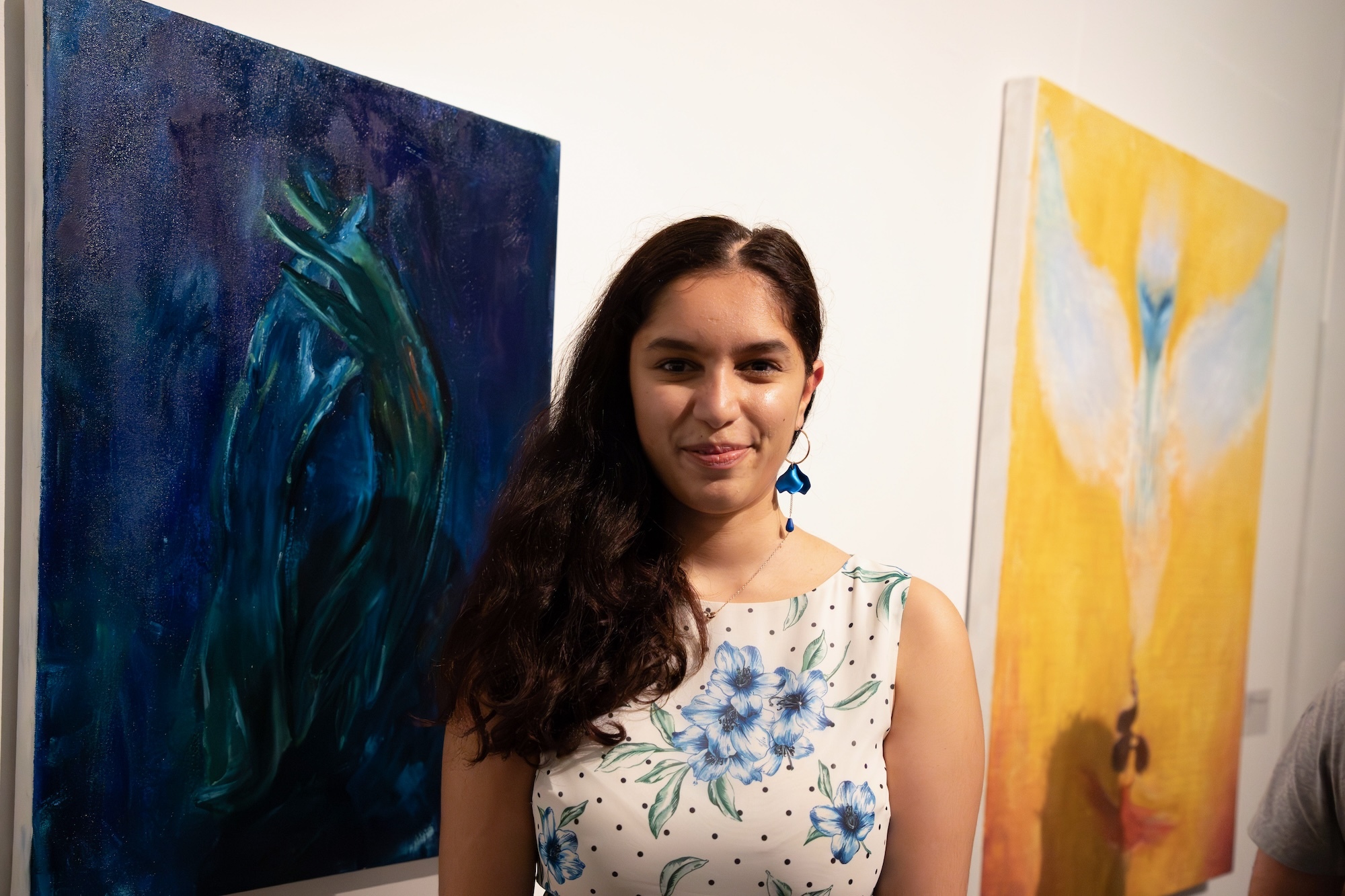 Artist A Z Rizvi standing between two paintings on display at Poole Lighthouse.