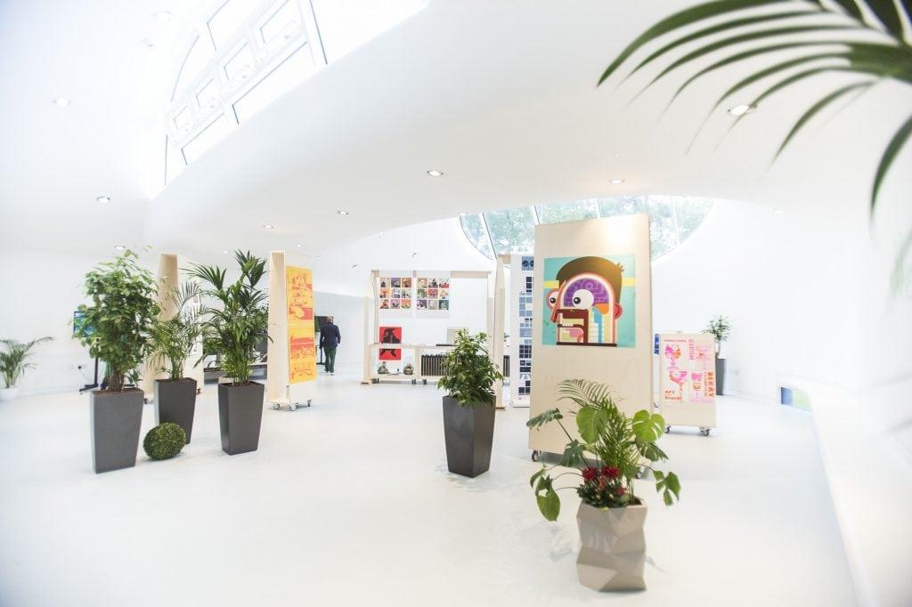 Illustration work displayed in the Drawing Studio at AUB. The work is surrounded by plants and lit but a large oval glass window