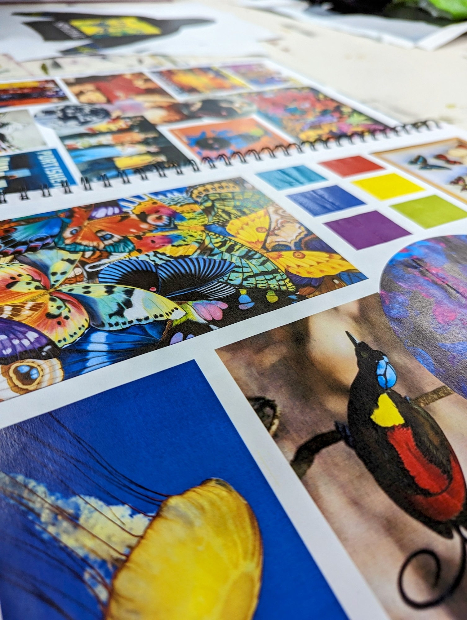Close-up of a sketchbook or portfolio showing various animal artworks, photos and mood boards.