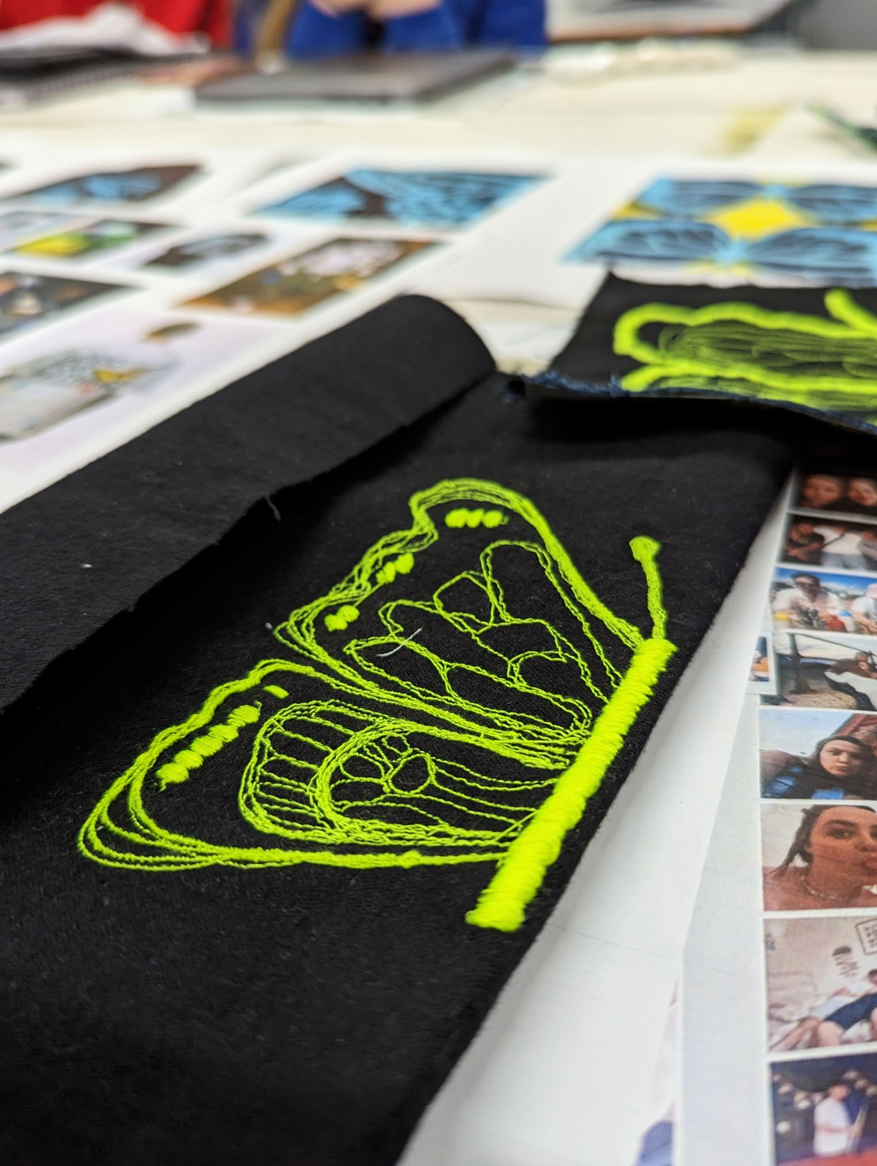 Close-up of a black piece of fabric with a bright yellow-green crown-like icon embroidered onto it.