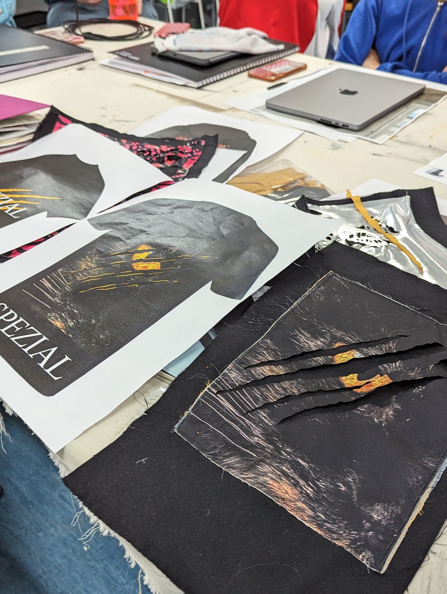 A table with a T-shirt design of a wolf's eye with claw marks scratched across it, next to the prototype T-shirt.
