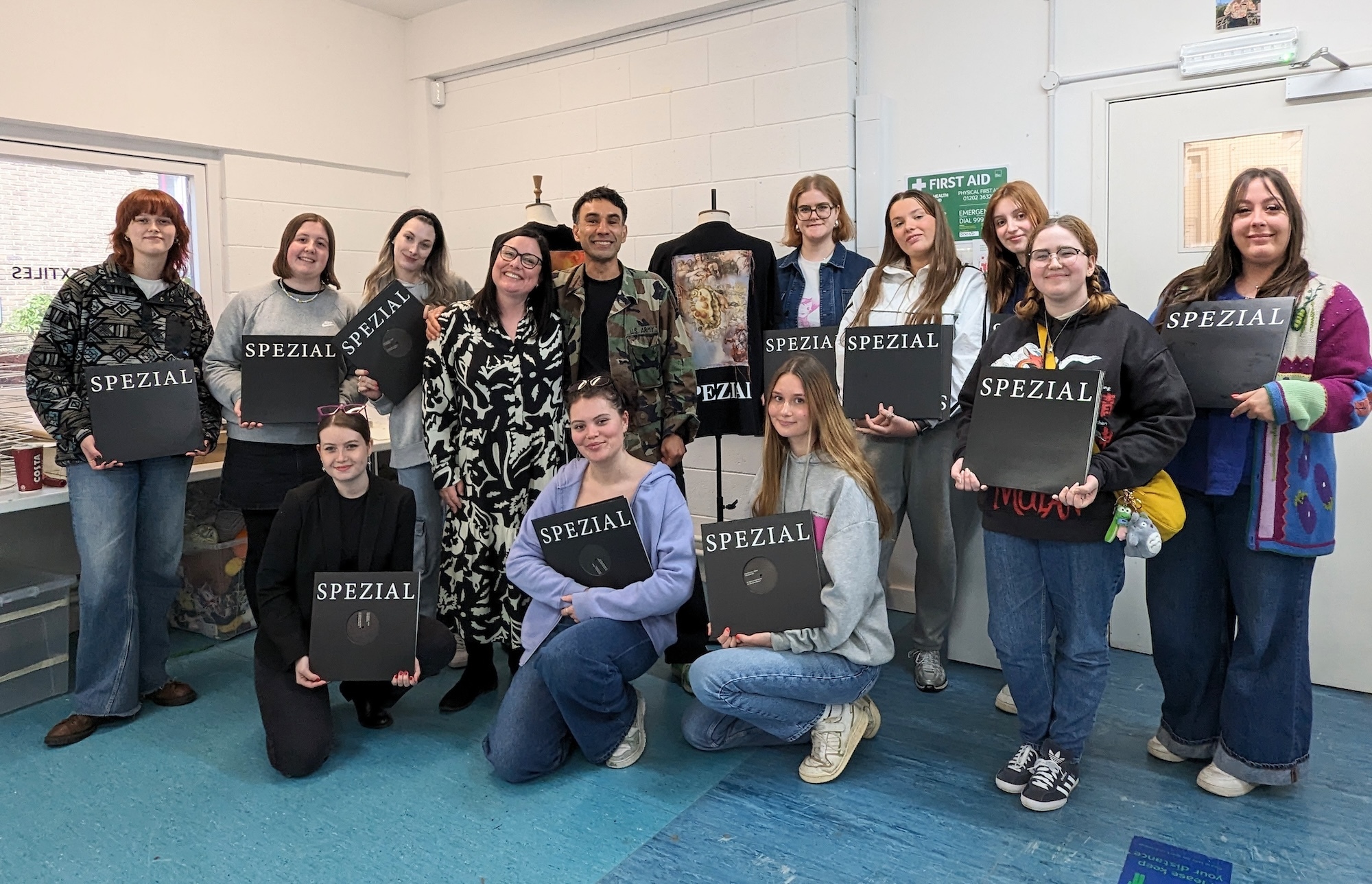 A group of BA (Hons) Textiles Design students posing for a photo at Richmond Classics, Bournemouth, all holding vinyl record cases with the SPEZIAL logo on it.