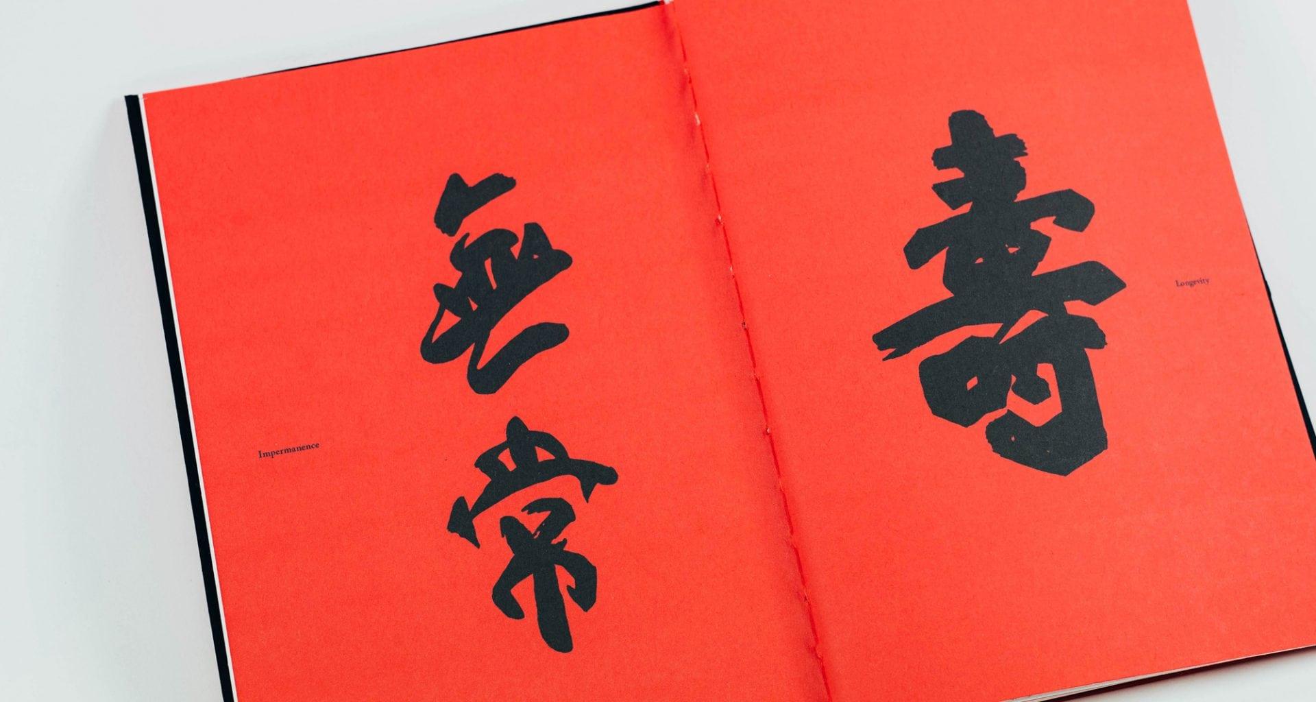 A book open to a double-page spread. The pages are red and have Chinese characters on them.
