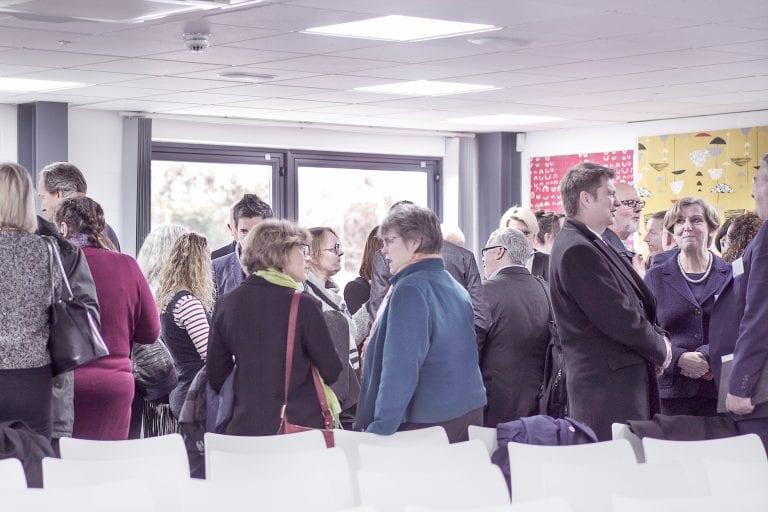 A crowd of people gathers in front of a series of empty seats