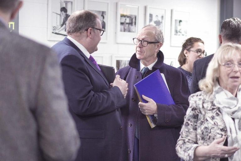 A group of people gather and converse in a gallery space