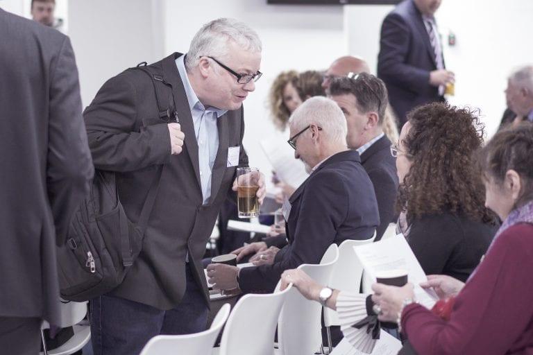 Two people talk while others take their seats for a talk