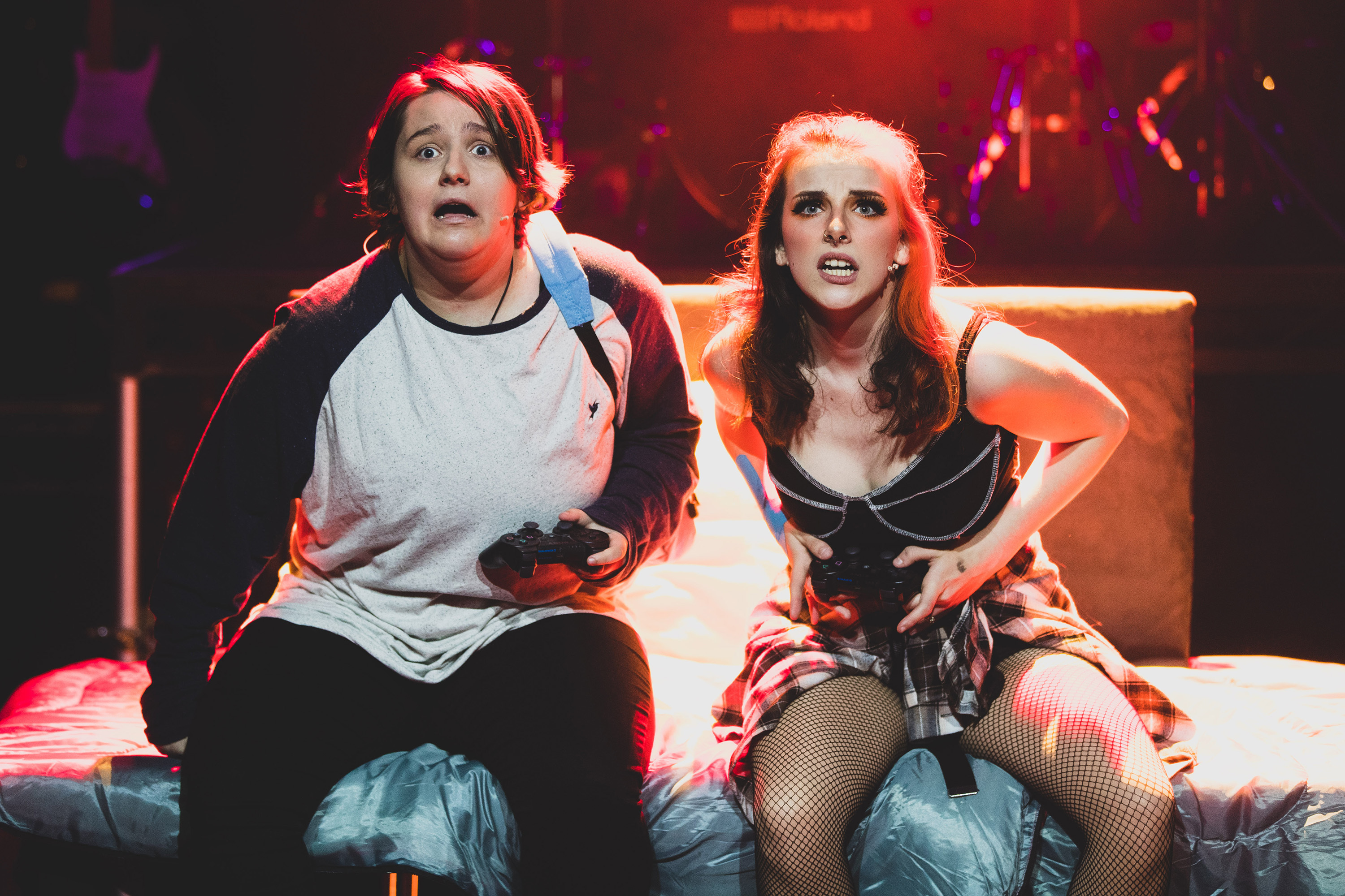 FdA Performing Arts students from Bournemouth and Poole College on stage as part of the production of Be More Chill, they look like they're dressed as teens in a teen bedroom with one holding an Xbox controller