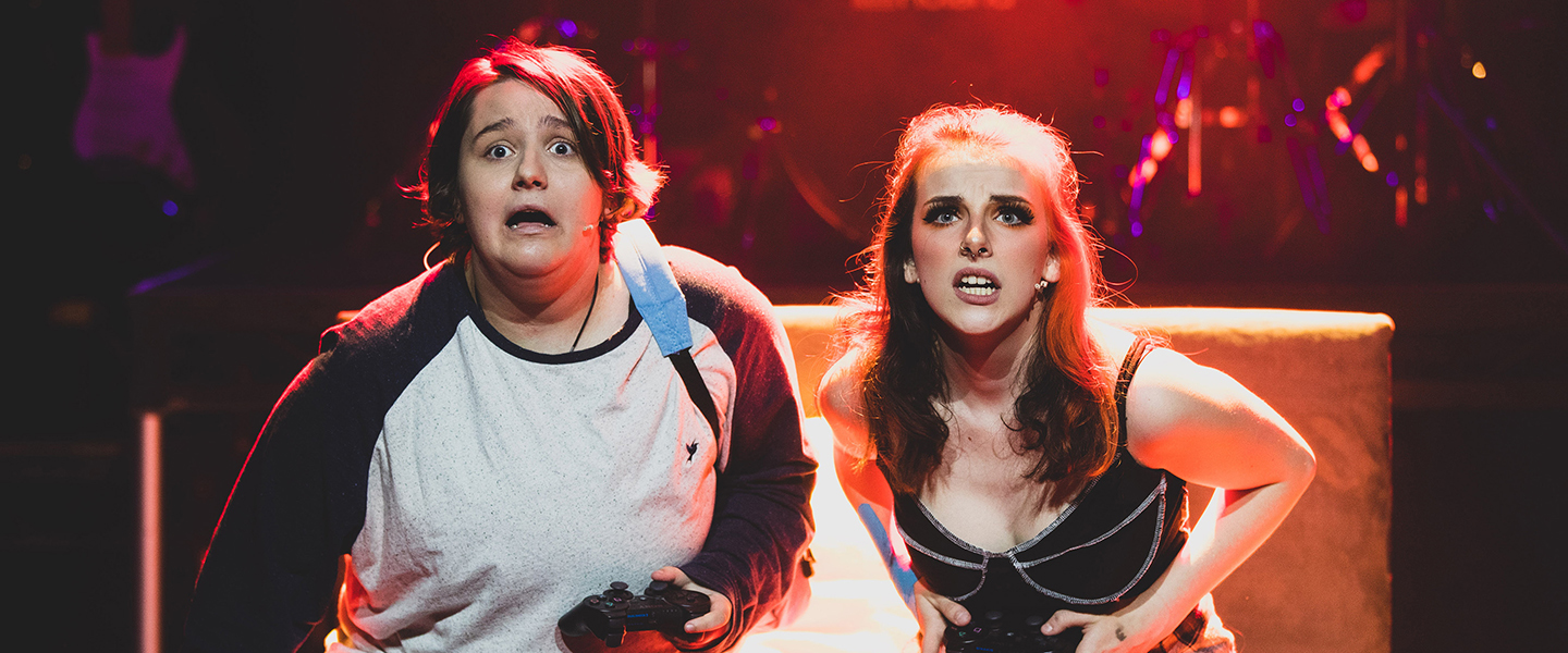 FdA Performing Arts students from Bournemouth and Poole College on stage as part of the production of Be More Chill, they look like they're dressed as teens in a teen bedroom with one holding an Xbox controller
