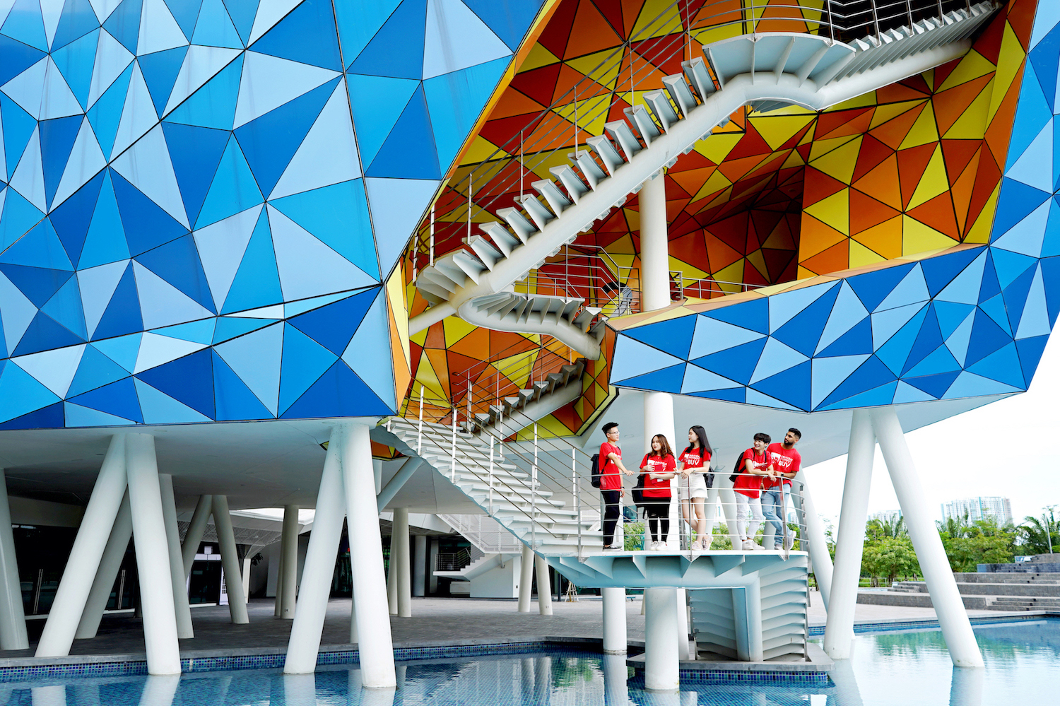 A group of students standing on a balcony outside an abstract building at BUV.