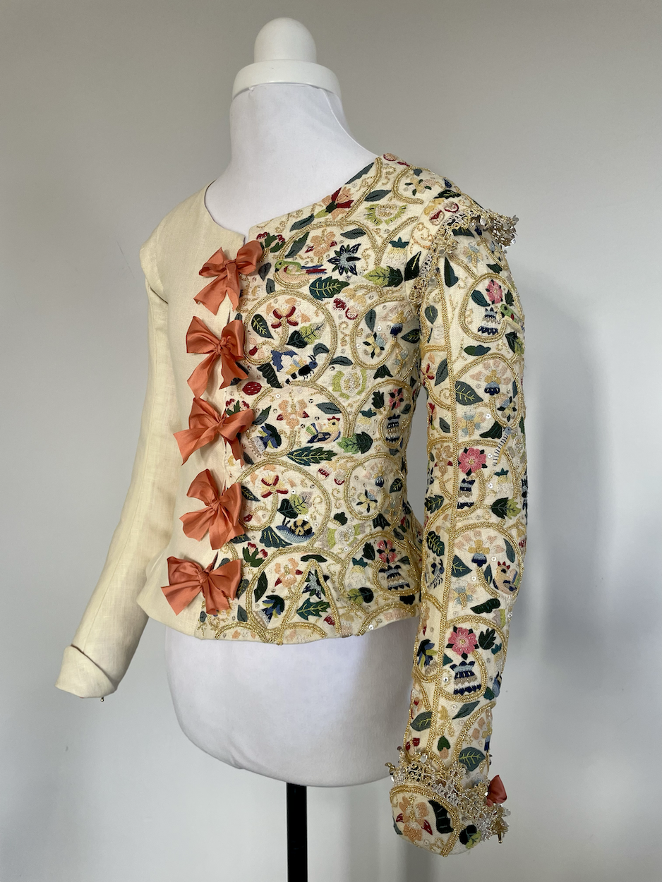 A 1610s jacket with ornate embroidery on one side, displayed on a mannequin.