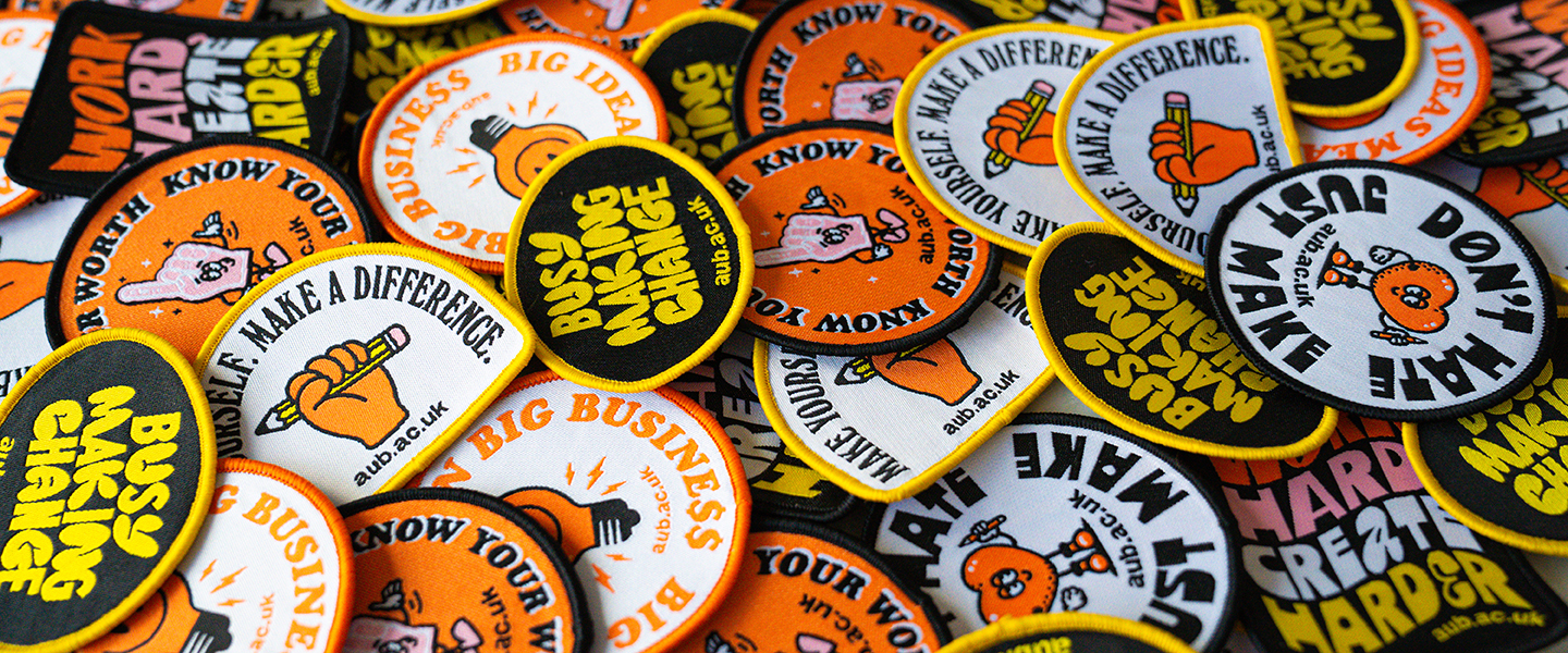 a pile of fabric badges from AUB's 'change the world' campaign