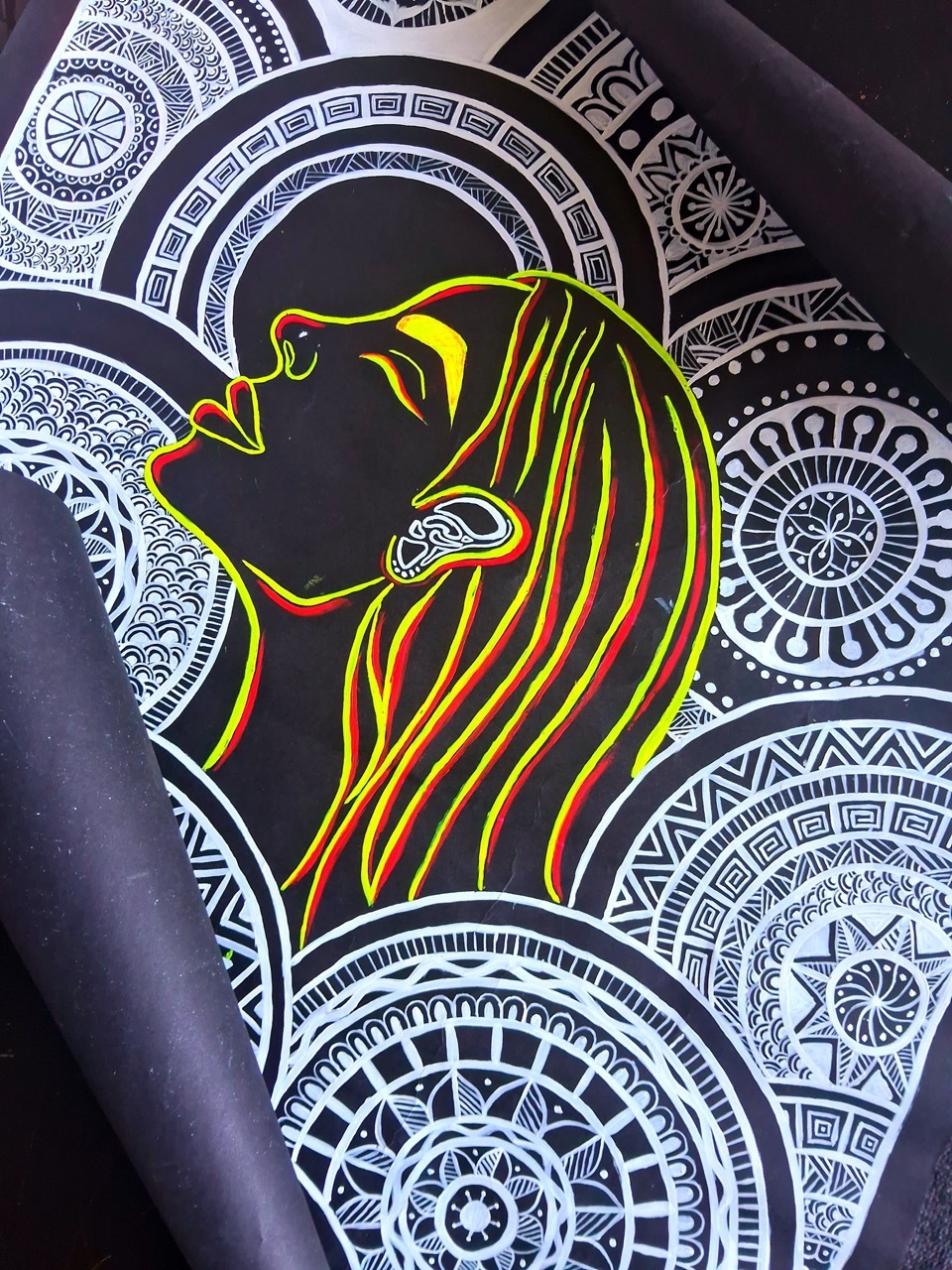 Illustrated yellow/red outline of a woman surrounded by white mandala illustrations, black background.