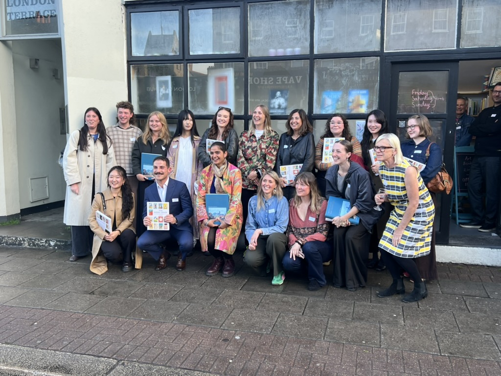 A large group of people pose for a photo holding Batsford Prize awards outside a bookshop